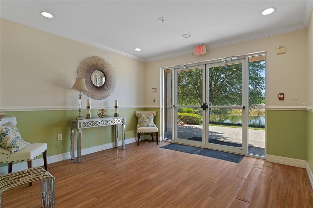 A lobby features wood-look tile flooring, a mirrored console table, and glass doors overlooking a pond — 7986 SOUTHERN PINES DRIVE UNIT 536, BROOKSVILLE, FL