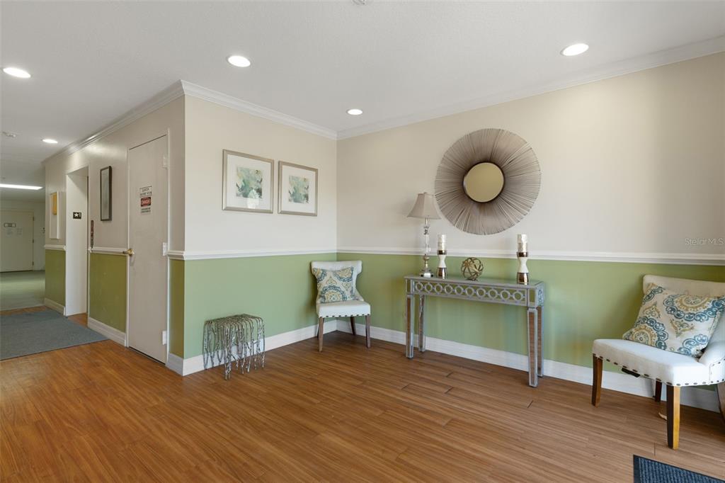 A hallway features wood-look flooring, two-tone walls, a console table, and two accent chairs — 7986 SOUTHERN PINES DRIVE UNIT 536, BROOKSVILLE, FL