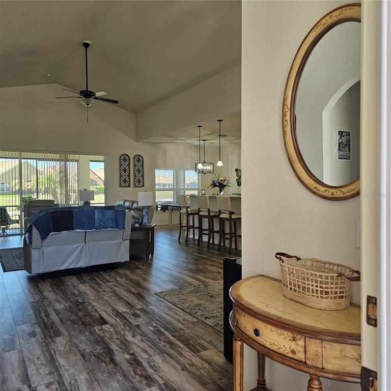 An entryway with a console table and mirror opens into a living room with wood-look flooring — 1347 OAKMONT DRIVE, WINTER HAVEN, FL