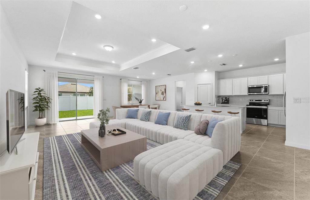 A bright open-concept living room and kitchen featuring a large sectional sofa and tile flooring — 4018 BIG SKY DRIVE, SPRING HILL, FL