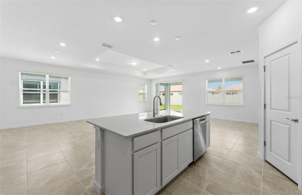 A kitchen island with a stainless steel sink sits in a bright, open-concept room — 4018 BIG SKY DRIVE, SPRING HILL, FL