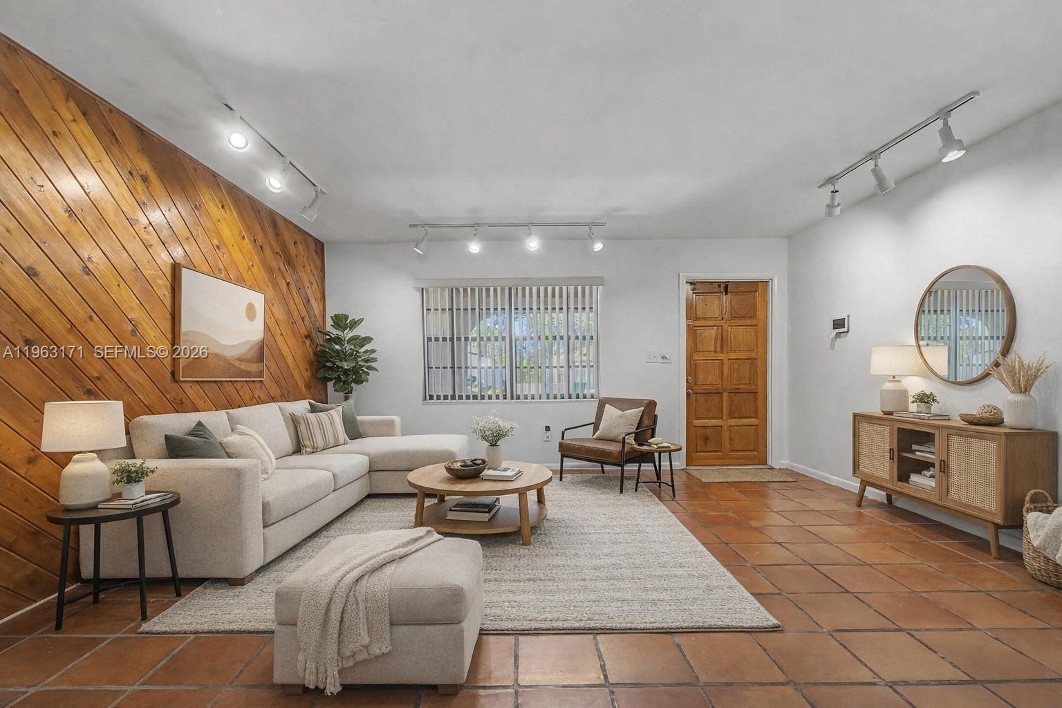 A living room features a wood-paneled accent wall, tile flooring, and a neutral sectional sofa — 7354 SW 135th Ct, Miami FL 33183, MIAMI, FL