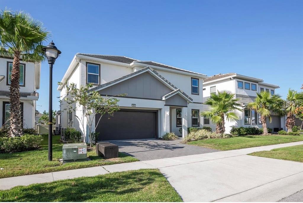 A two-story suburban house with a gray garage door, white stucco siding, and palm trees — 2659 CALISTOGA AVENUE, KISSIMMEE, FL