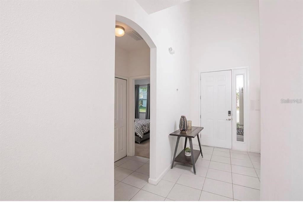 A bright entryway features white walls, tiled floors, an arched doorway, and a wooden console table — 2659 CALISTOGA AVENUE, KISSIMMEE, FL