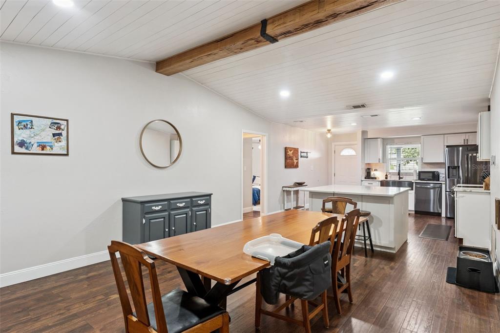 A dining area with a wooden table, dark wood floors, and a kitchen island — 1404 BEVERLY LANE, CASSELBERRY, FL