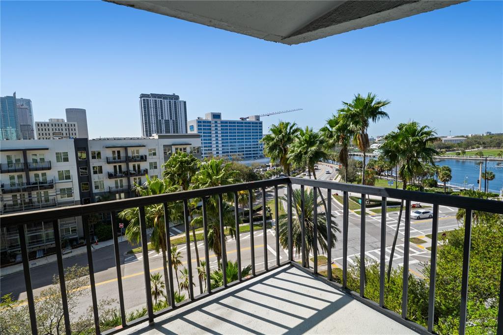 A balcony with a metal railing overlooks a city street, palm trees, and a waterfront — 201 W LAUREL STREET UNIT 712, TAMPA, FL