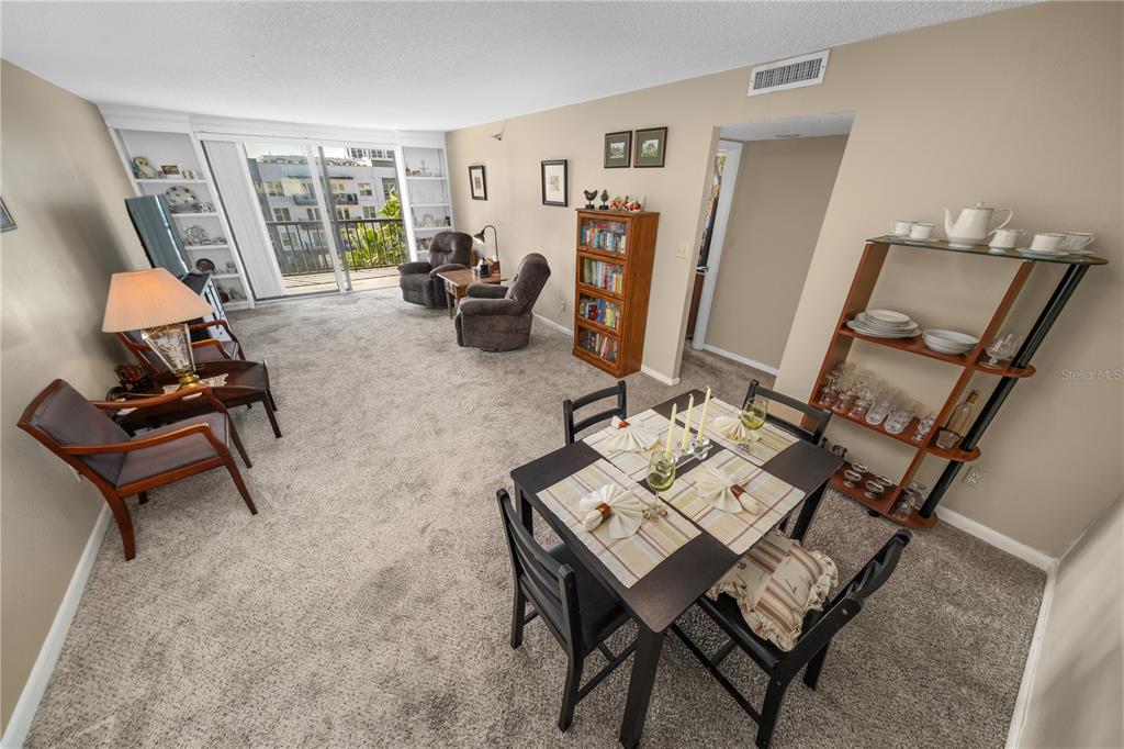 A living and dining area with carpeted floors, a balcony, and a dining table set — 201 W LAUREL STREET UNIT 712, TAMPA, FL