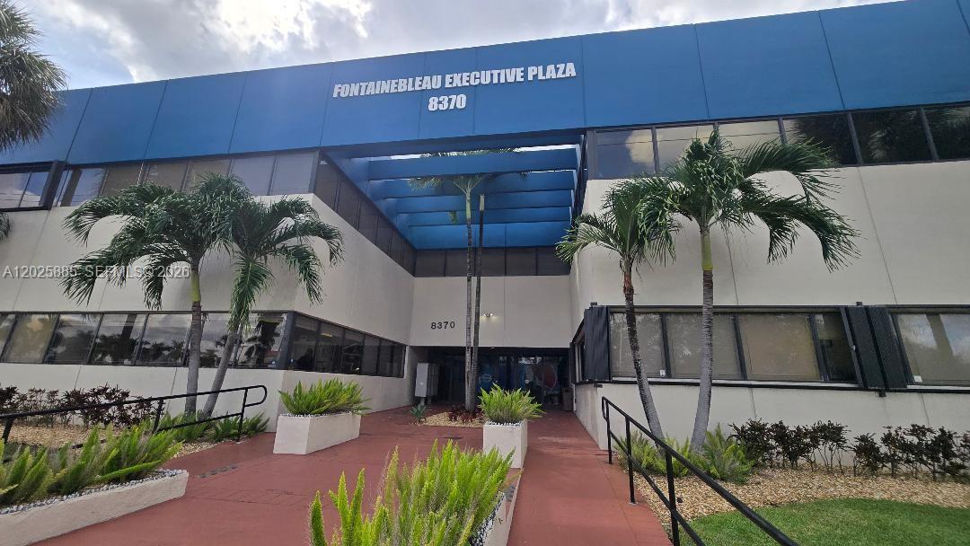 The exterior of a two-story office building features a blue facade and palm trees — 8370 W Flagler St # 246, Miami FL 33144, MIAMI, FL