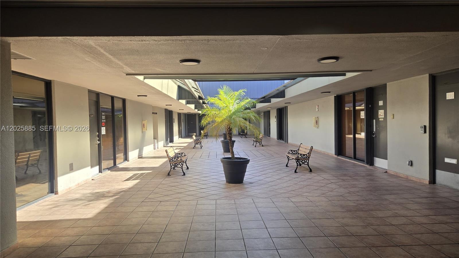 An outdoor courtyard features tiled flooring, several benches, and a central potted palm tree — 8370 W Flagler St # 246, Miami FL 33144, MIAMI, FL
