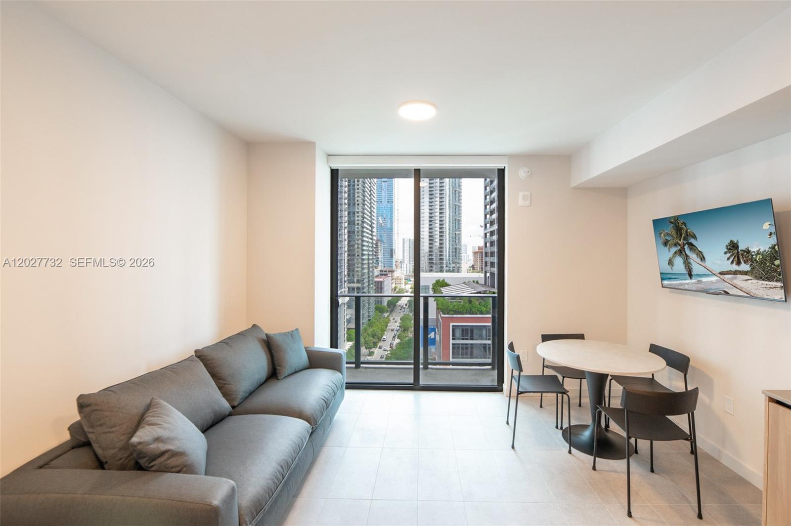 A living and dining area features a gray sofa, a round table, and a balcony view — 121 NE 5th St # 1809, Miami FL 33132, MIAMI, FL