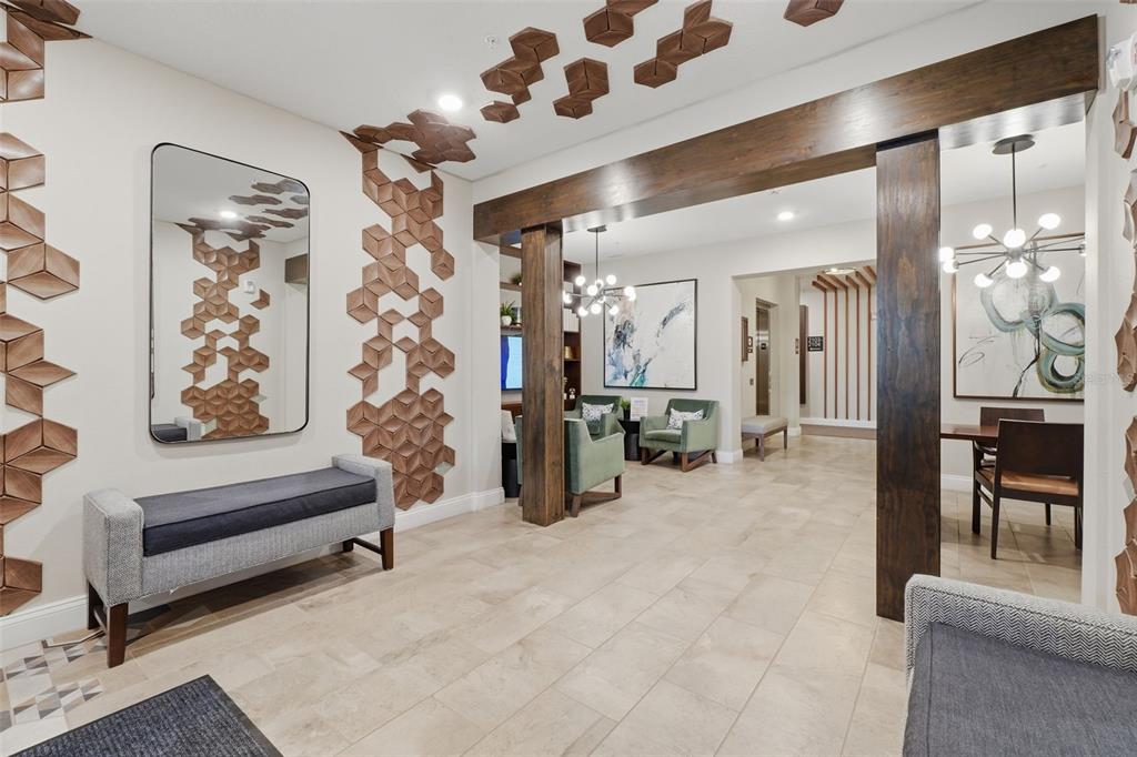 A modern lobby features geometric wood wall art, a gray bench, and dark wood beams — 7505 LAUREATE BOULEVARD UNIT 2408, ORLANDO, FL