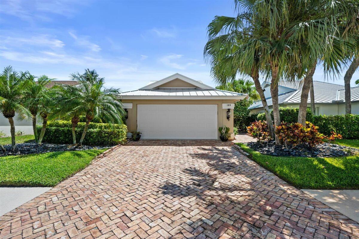 A brick driveway leads to a single-story house with a white garage door and palm trees — 109 Seashore Drive, Jupiter FL 33477, JUPITER, FL