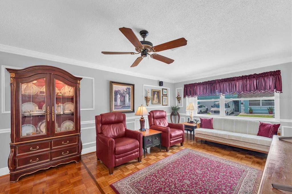A living room features a large wooden hutch, two red leather chairs, and a striped sofa — 6915 VERSAILLES N, PINELLAS PARK, FL