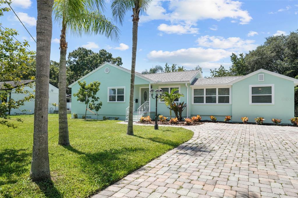 A light green single-story house features a paved driveway, palm trees, and a front lawn — 814 W INDIANA AVENUE, TAMPA, FL