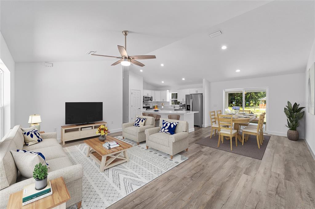 An open-concept living and dining area features light wood flooring, white walls, and a kitchen — 5861 NW 64TH STREET, OCALA, FL