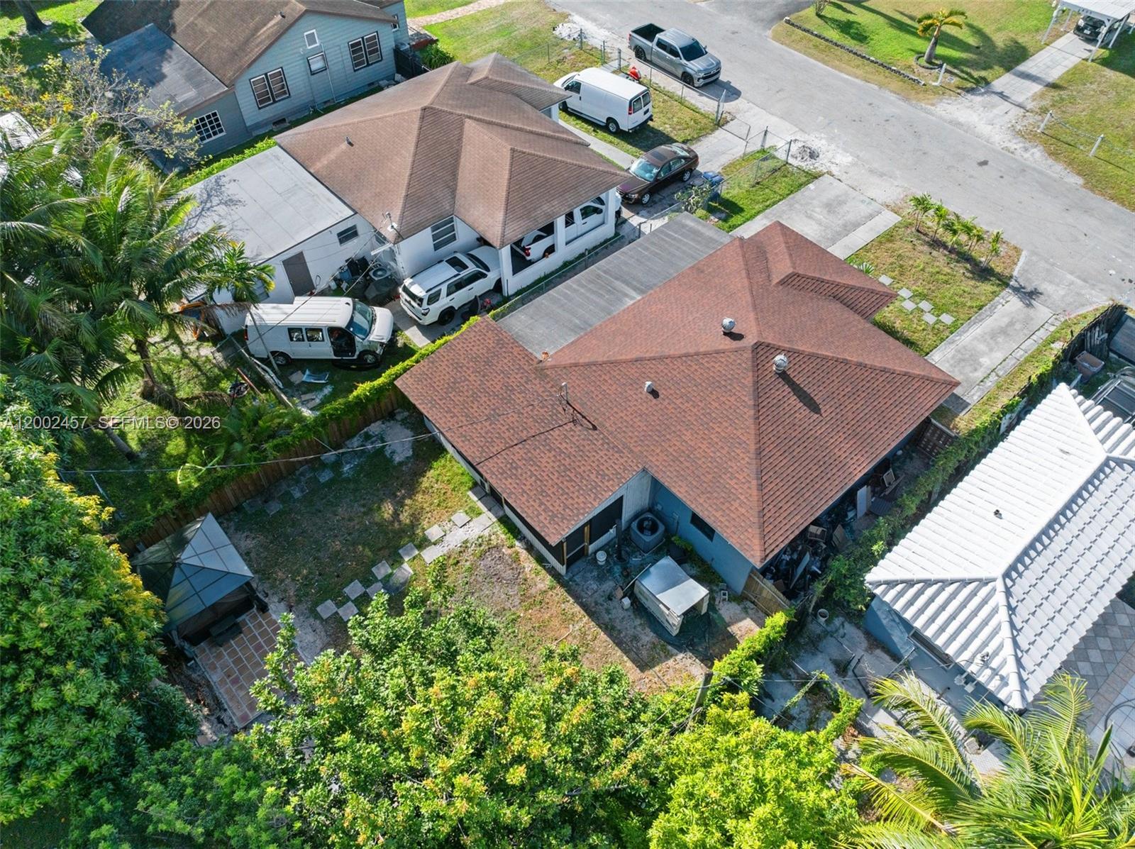 An aerial view shows two adjacent houses with brown roofs, driveways, and backyard landscaping — 2410 Jackson St, Hollywood FL 33020, HOLLYWOOD, FL
