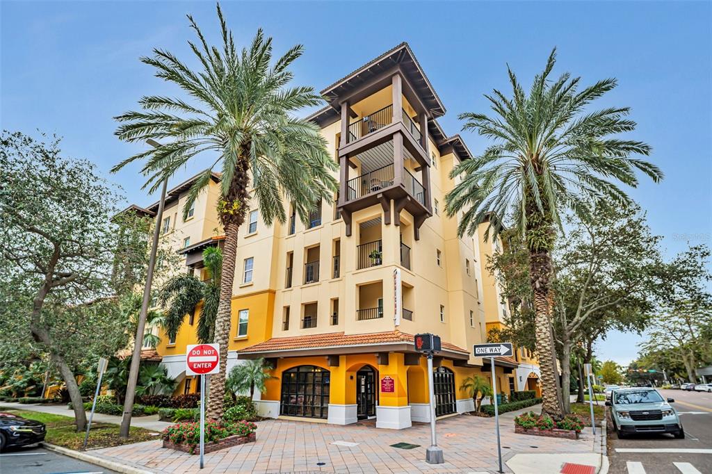 A multi-story yellow apartment building with balconies and palm trees on a sunny day — 100 4TH AVENUE S UNIT 224, ST PETERSBURG, FL