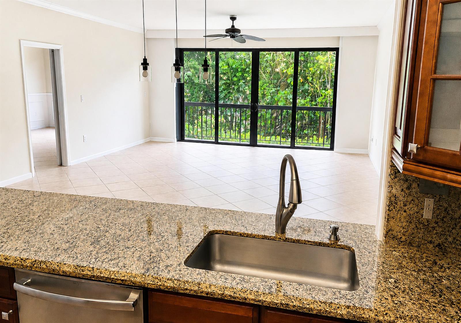 A kitchen island with a granite countertop and stainless steel sink overlooks an open living area — 70 Celestial Way # 108, Juno Beach FL 33408, JUNO BEACH, FL