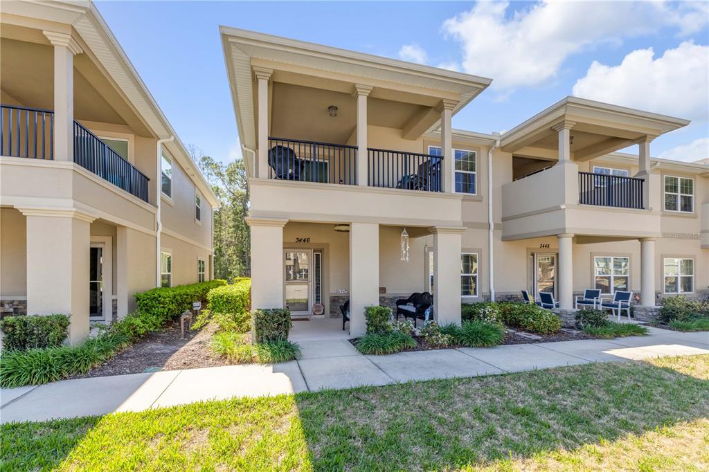 The exterior of a two-story apartment building features balconies, tan stucco walls, and stone accents — 3446 MEDICI BOULEVARD, NEW SMYRNA BEACH, FL