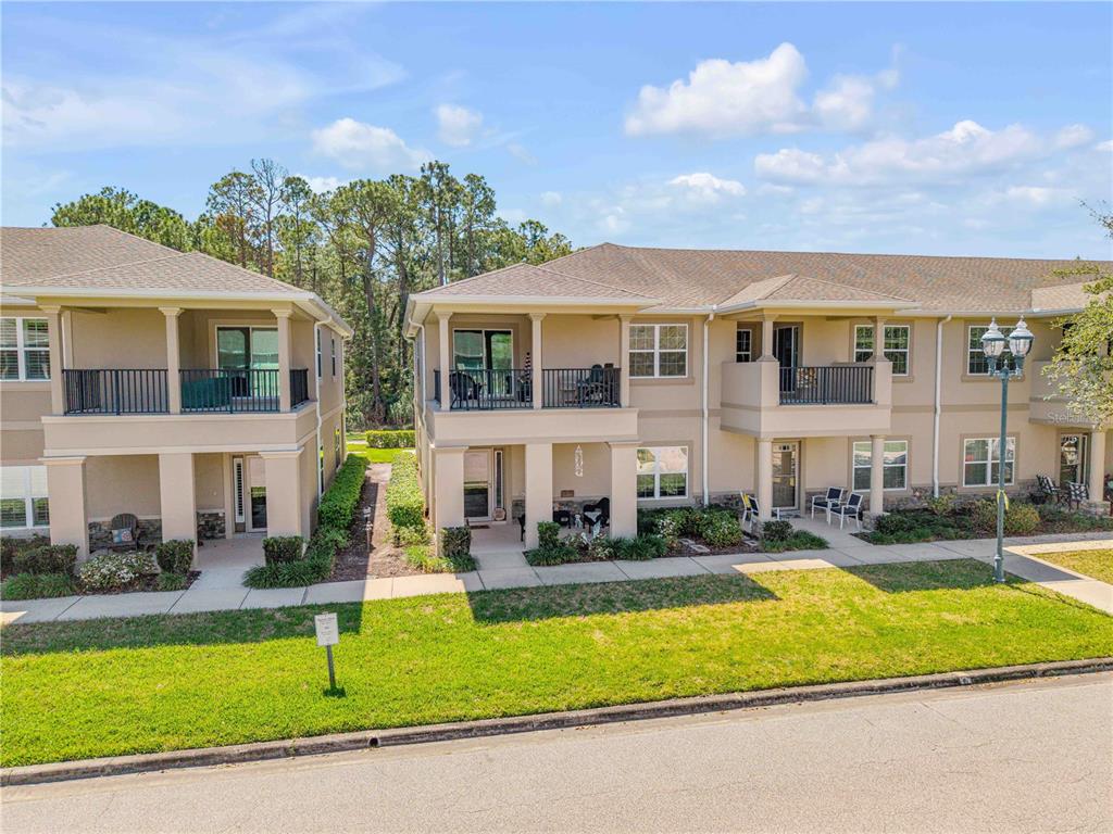 An exterior view of a two-story multi-family residential building with balconies and a front lawn — 3446 MEDICI BOULEVARD, NEW SMYRNA BEACH, FL