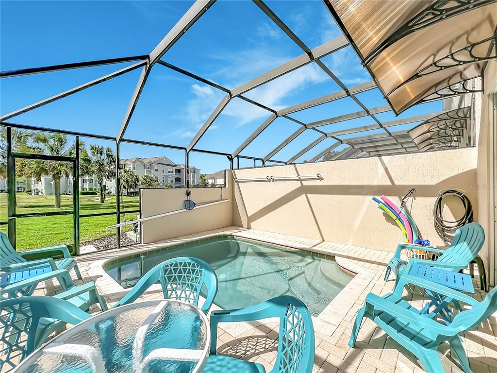 A screened-in patio features a small plunge pool, patio furniture, and a view of buildings — 8104 PRINCESS PALM LANE, KISSIMMEE, FL
