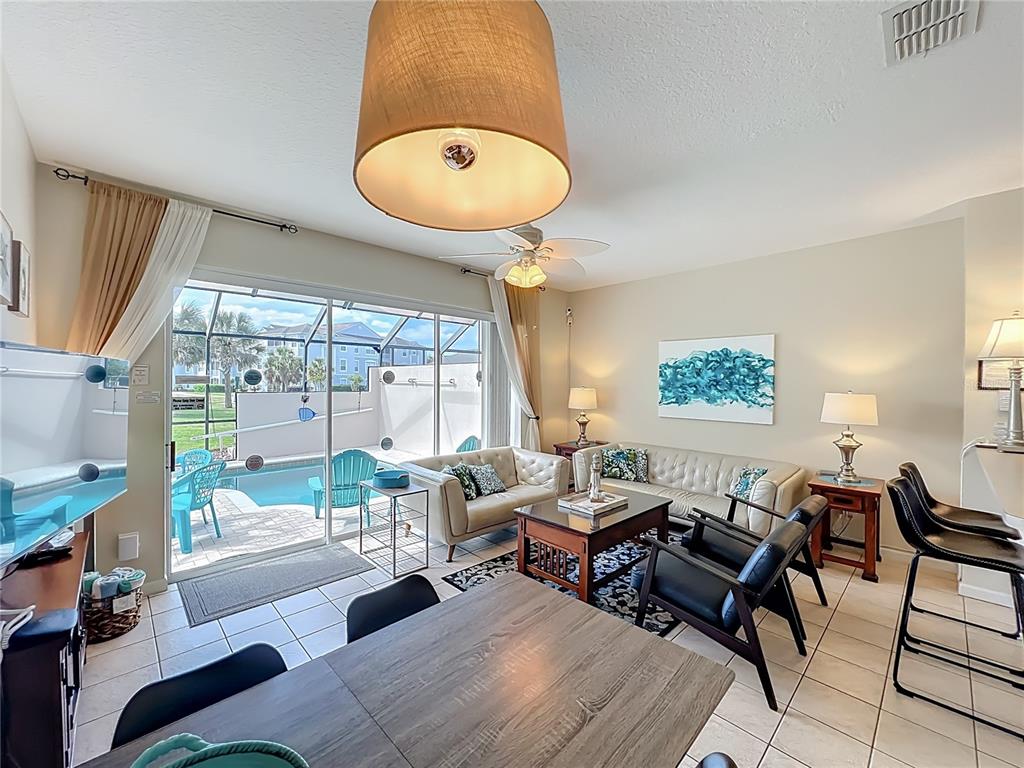 A living room with tile floors, a dining area, and sliding doors opening to a pool — 8104 PRINCESS PALM LANE, KISSIMMEE, FL