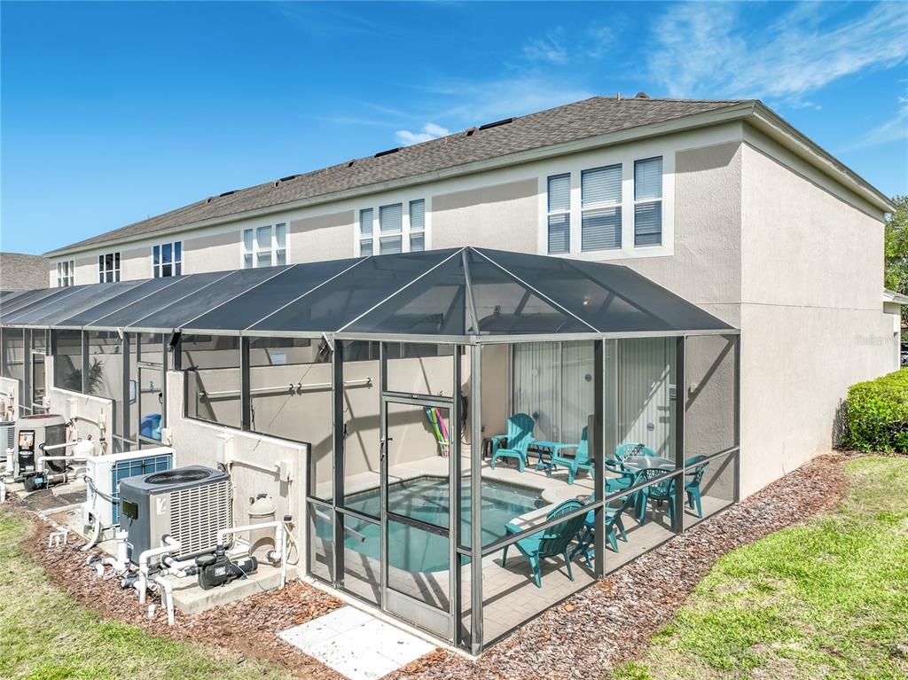 A two-story townhouse exterior features a screened-in patio with a small private pool — 8104 PRINCESS PALM LANE, KISSIMMEE, FL