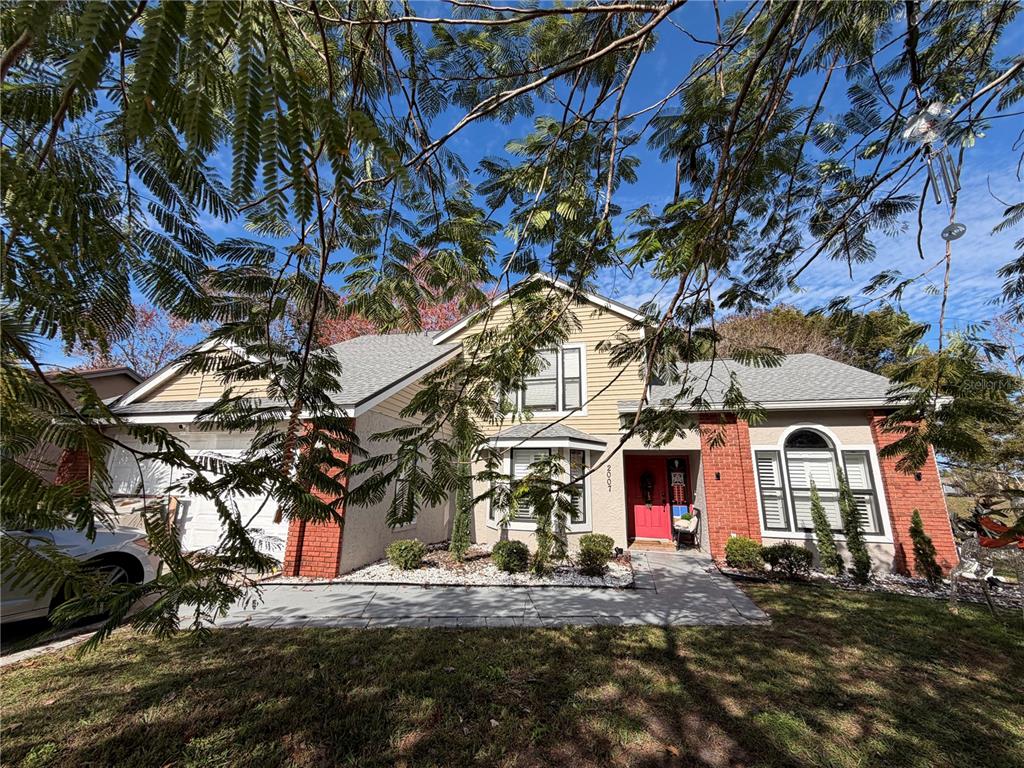 A two-story house with a red brick facade, yellow siding, and a bright red front door — 2007 NORFIELD COURT, ORLANDO, FL