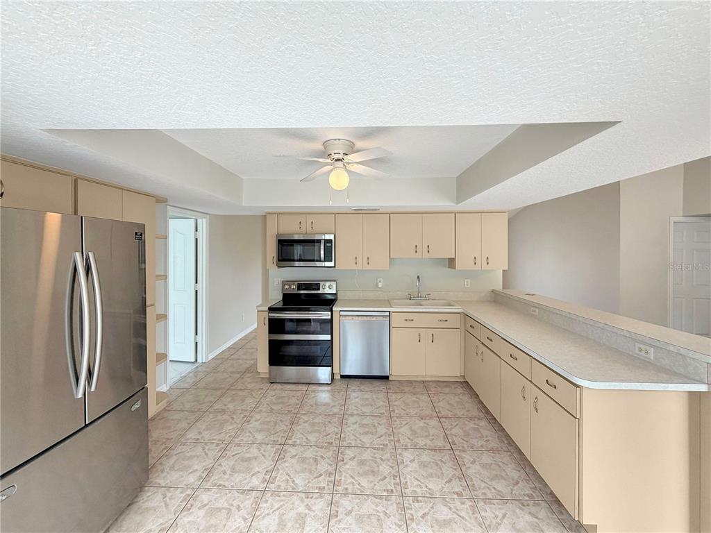 A kitchen with light-colored cabinets, stainless steel appliances, and tile flooring — 17052 SW 39TH CIRCLE, OCALA, FL