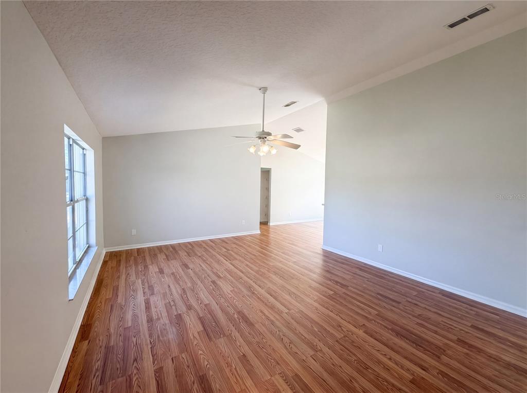 An empty room features light gray walls, wood-look flooring, a ceiling fan, and a window — 17052 SW 39TH CIRCLE, OCALA, FL