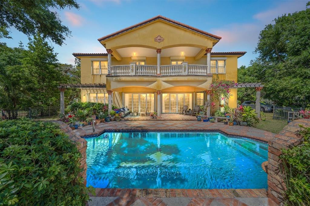A two-story yellow house with a balcony and a swimming pool in the backyard — 9340 S TROPICAL TRAIL, MERRITT ISLAND, FL