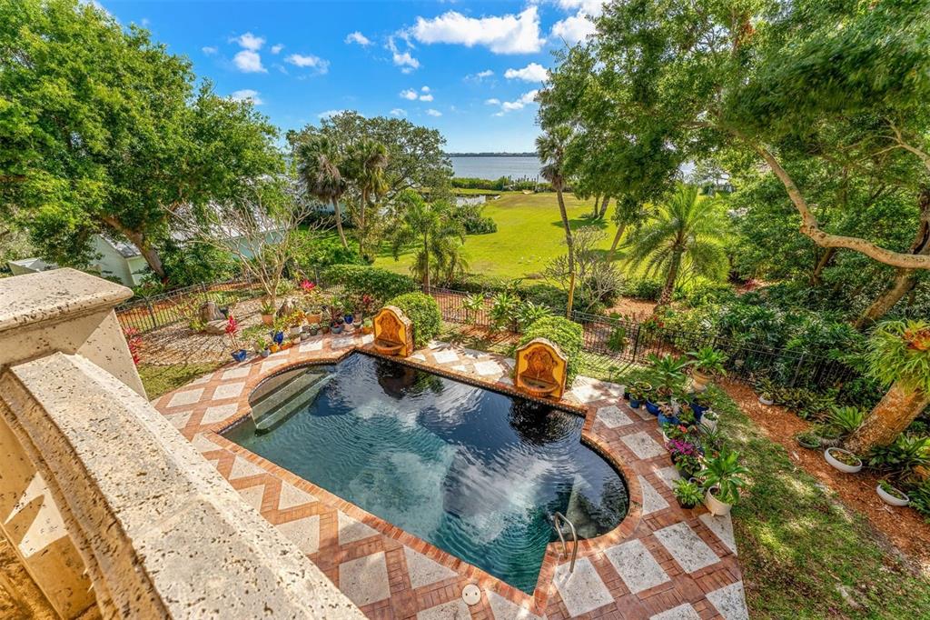 An elevated view of a backyard swimming pool with stone decking and two decorative fountains — 9340 S TROPICAL TRAIL, MERRITT ISLAND, FL