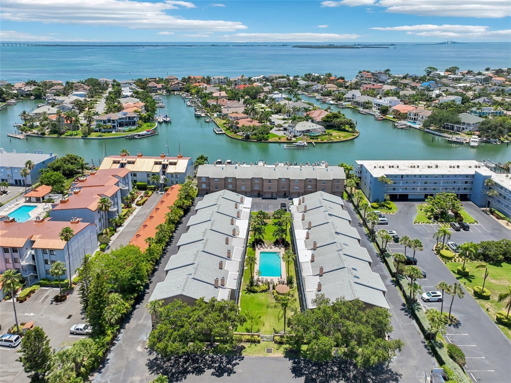 An aerial view shows a residential complex with a central pool and nearby waterfront canals — 637 PINELLAS BAYWAY UNIT 105, TIERRA VERDE, FL