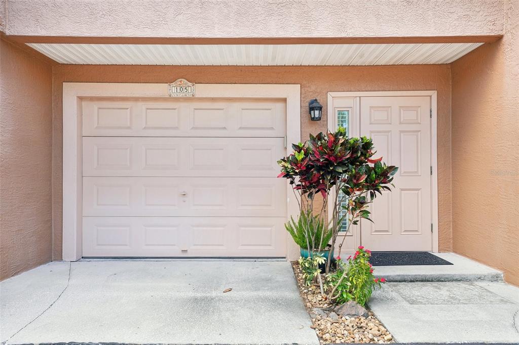 A tan stucco exterior features a garage door labeled 105 and an adjacent front door — 637 PINELLAS BAYWAY UNIT 105, TIERRA VERDE, FL