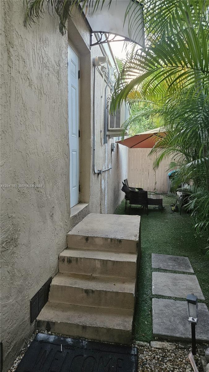 A concrete staircase leads to a white door beside a narrow outdoor patio area — 965 NE 146th St, North Miami FL 33161, NORTH MIAMI, FL
