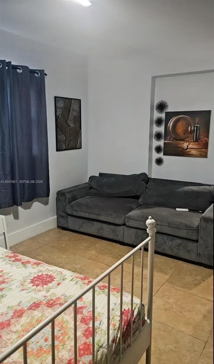 A bedroom features a gray corduroy sofa, a bed with a floral quilt, and tiled flooring — 965 NE 146th St, North Miami FL 33161, NORTH MIAMI, FL