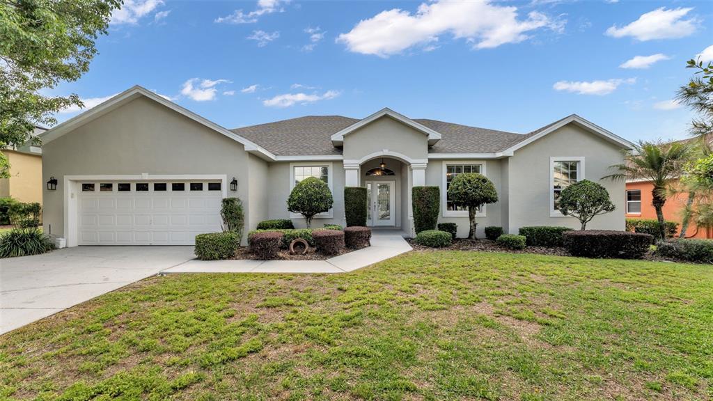 A single-story house with a beige stucco exterior, a two-car garage, and a landscaped yard — 2985 VINTAGE VIEW CIRCLE, LAKELAND, FL