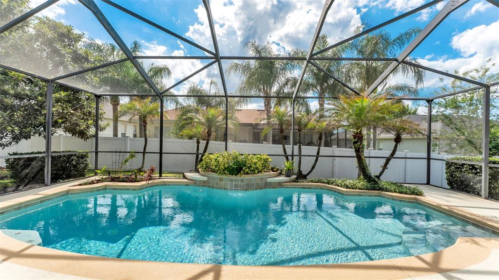 A swimming pool with a raised planter and waterfall feature inside a screened-in patio enclosure — 2985 VINTAGE VIEW CIRCLE, LAKELAND, FL