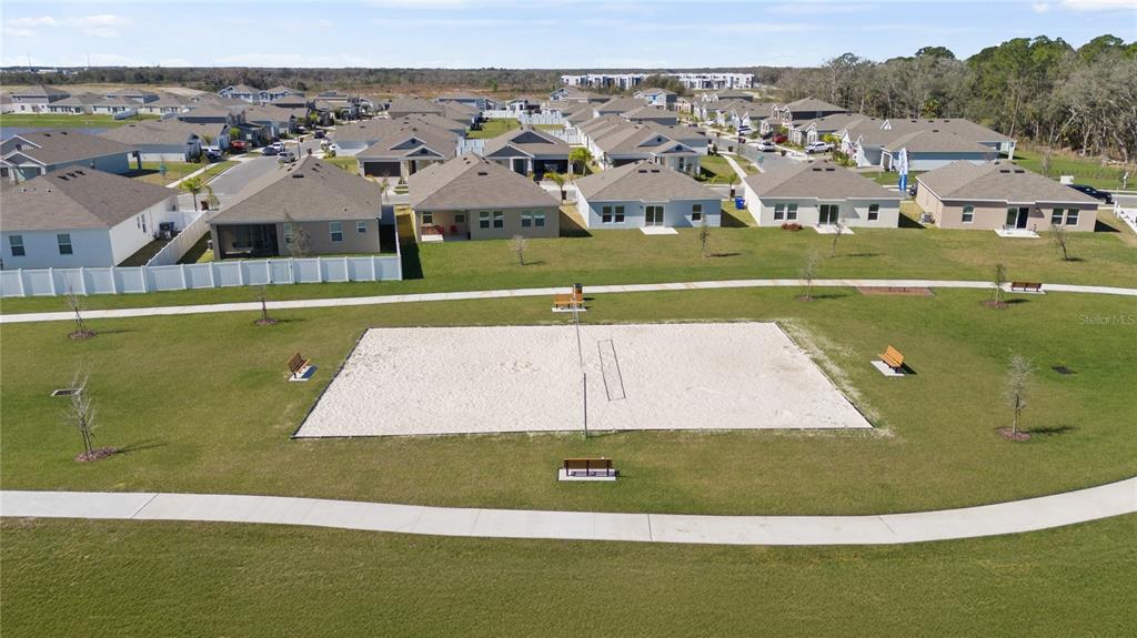 An aerial view shows a sand volleyball court surrounded by a grassy lawn and houses — 4561 GOLDEN KNIGHT TRAIL, KISSIMMEE, FL