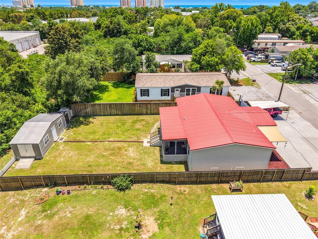 An aerial view shows a house with a red metal roof and a detached shed — 128 N VESTAVIA STREET, PANAMA CITY BEACH, FL