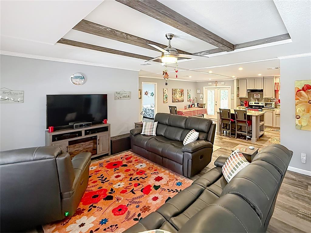 A living room with gray leather furniture, a floral rug, and wood-beam ceiling accents — 128 N VESTAVIA STREET, PANAMA CITY BEACH, FL
