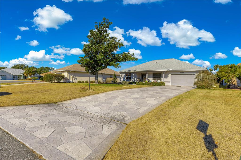 A single-story house with a stamped concrete driveway and a large tree in the yard — 11255 SE 175TH LN, SUMMERFIELD, FL
