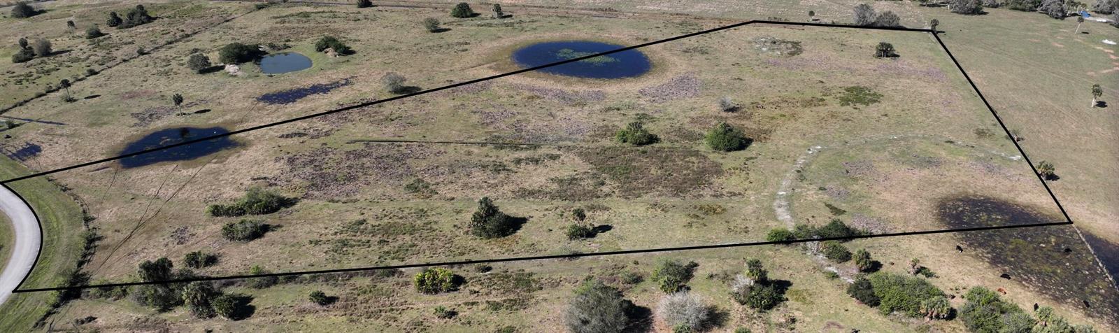 An aerial view shows a large, grassy plot of land with several small ponds — 6572 SE 26th Trail, Okeechobee FL 34974, OKEECHOBEE, FL