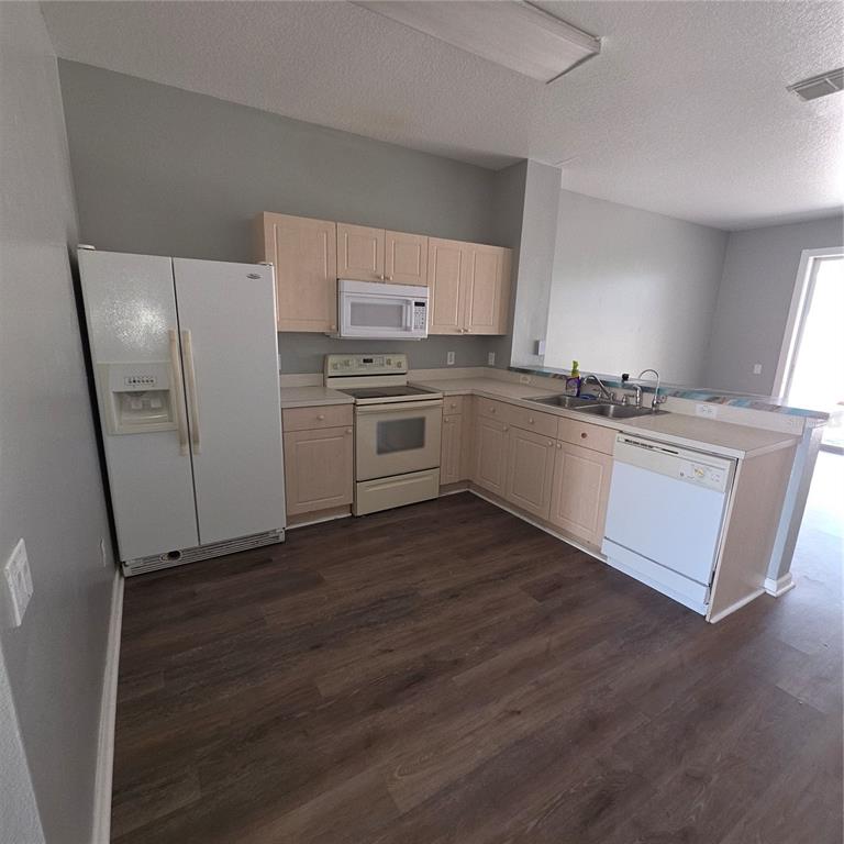 A kitchen features light wood cabinets, white appliances, and dark wood-look flooring — 2403 SILVER PALM DRIVE, KISSIMMEE, FL