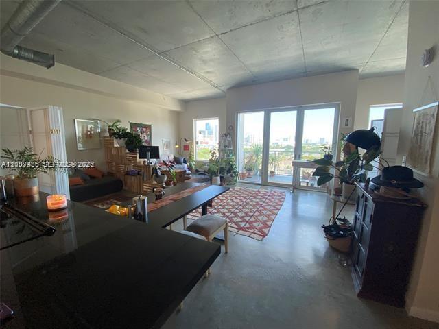 An open-concept living area features a kitchen island, concrete ceilings, and a balcony with views — 10 SW South River Dr # 909, Miami FL 33130, MIAMI, FL
