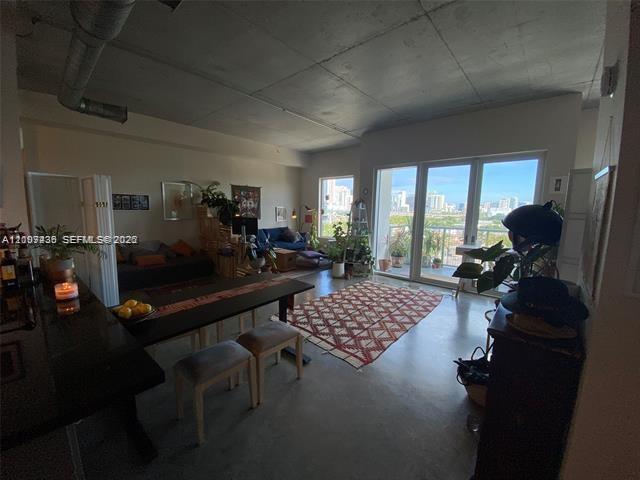 An open-concept living area features concrete ceilings, a dining table, and a balcony with city views — 10 SW South River Dr # 909, Miami FL 33130, MIAMI, FL