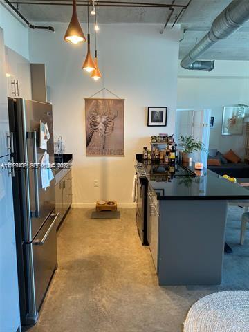 A modern kitchen features stainless steel appliances, dark countertops, and industrial-style exposed ceiling pipes — 10 SW South River Dr # 909, Miami FL 33130, MIAMI, FL