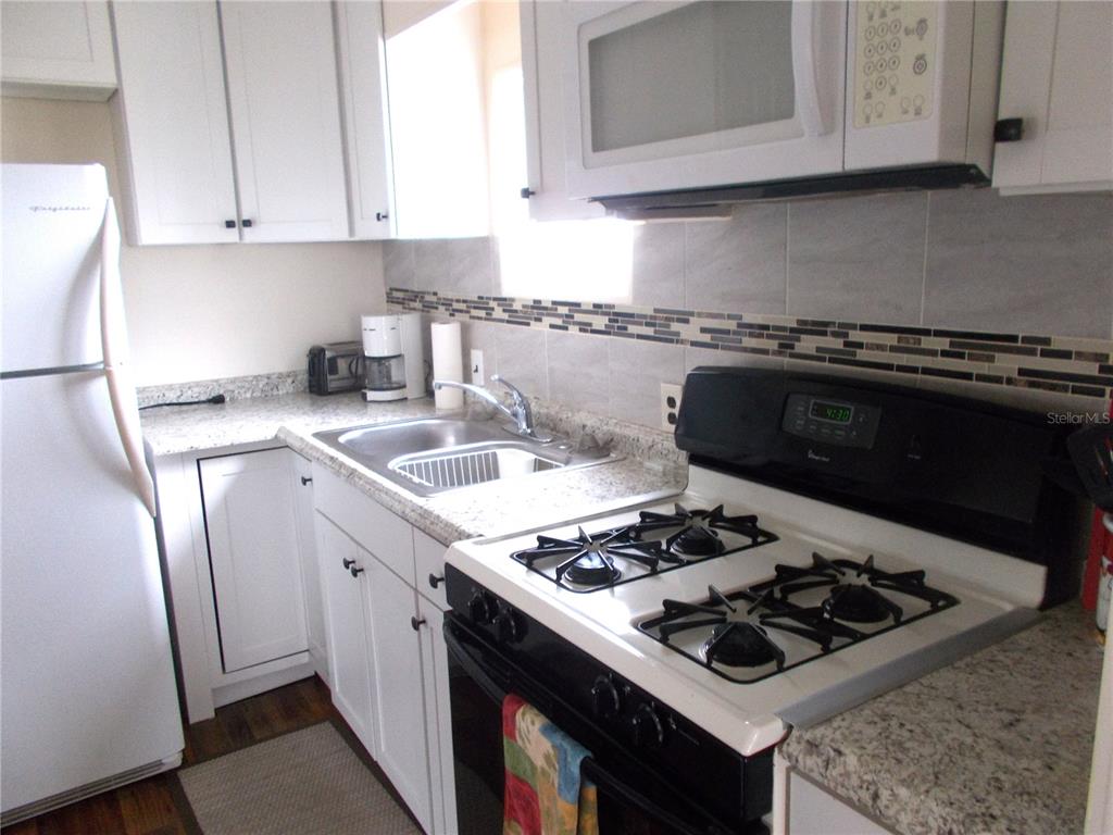 A kitchen features white cabinets, granite countertops, a stainless steel sink, and a gas range — 6821 OCEAN COURT, NORTH PORT, FL