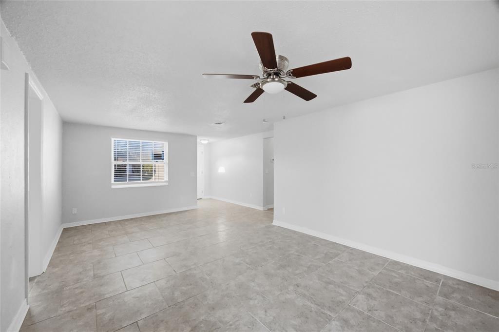 An empty room with light gray walls, tile flooring, and a ceiling fan — 6225 WESTPORT DRIVE, PORT RICHEY, FL