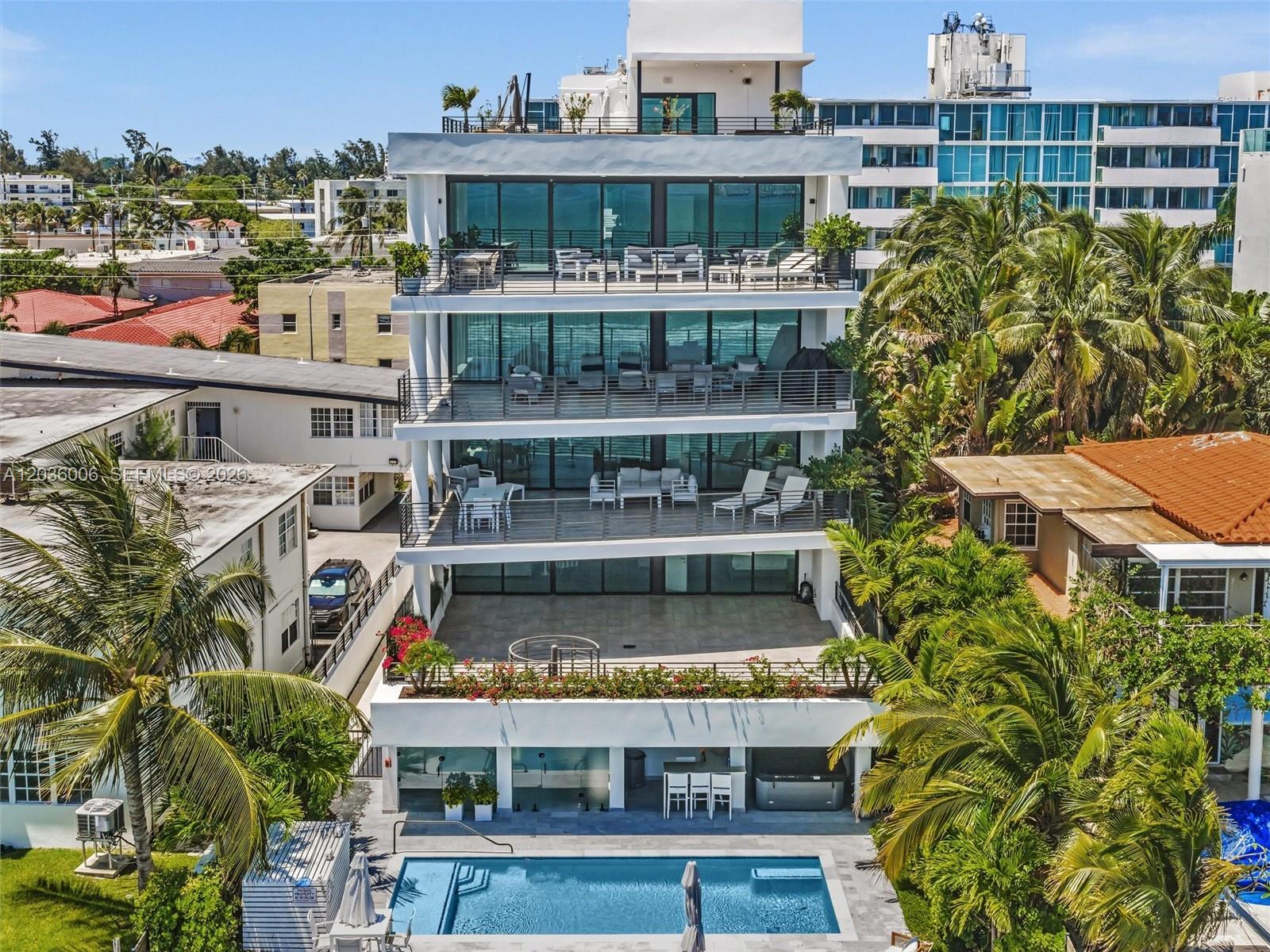 An exterior view of a multi-story modern building featuring balconies, a swimming pool, and landscaping — 1930 Bay Dr, Miami Beach FL 33141, MIAMI BEACH, FL